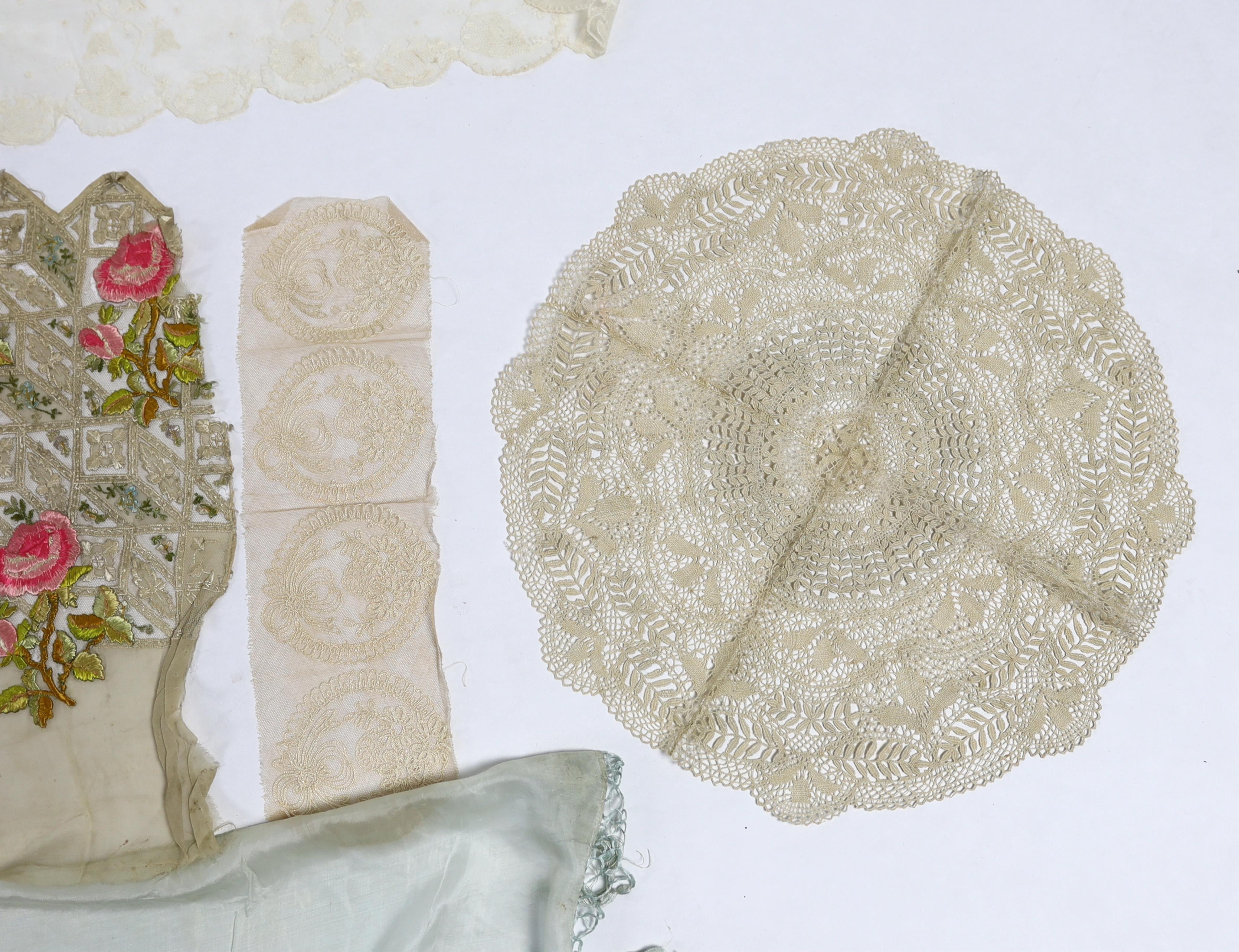 An early 20th century fine spun silk embroidered and fringed pelmet, a lace and polychrome embroidered border, possibly a panel to a dress, a needle run lace stole, a Normandy lace border to a circular mat, a bobbin lace